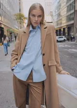 Abrigo largo color camel, con cuello de solapa, doble botonadura y bolsillos laterales con solapa. Confeccionado en mezcla de lana con forro interior.