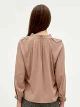 Blusa blanca de mangas largas con cuello fruncido y lazo.