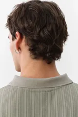 Remera polo verde salvia de punto texturizado, corte slim fit, manga corta, cuello clásico y tapeta con dos botones.