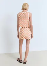 Falda corta de tejido crochet con diseño de flores en naranja y crema, bajo festoneado.