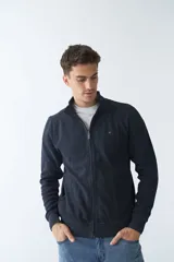 Campera marrón de algodón con cierre frontal, cuello alto, bolsillos laterales, puños y logo bordado en el pecho.