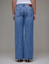 Jean de tiro alto de calce relajado, color azul denim. Tiene pretina con pasadores, botón y cierre. Delantera y trasera con bolsillos. Recortes verticales en el frente y recorte horizontal en el ruedo.