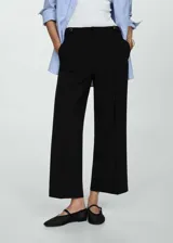 Pantalón azul marino de tiro medio y corte recto, con detalle de botones decorativos en la cintura y cierre frontal con botón, gancho y cremallera. Diseño crop.