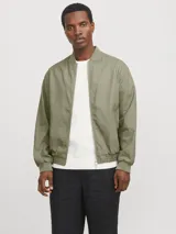 Campera bomber color verde claro, de tejido liviano de lino y algodón, con cuello tipo baseball, mangas largas con puños de canalé, cierre con cremallera y bolsillos delanteros.