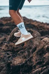 Championes color crema con suela blanca y logo blanco en el lateral.