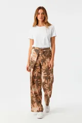 Pantalón de viscosa color beige con estampado de siluetas de leopardos en marrón y blanco. Corte palazzo, tiro alto y lazo ajustable en la cintura.