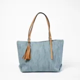 Bolso tipo tote de tela azul con textura, doble asa de cuero color camel y borla decorativa.