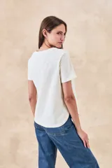 Remera blanca de manga corta con cuello redondo y bordados florales monocromáticos en relieve.