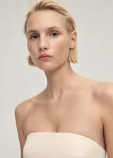 Top color crema con corte peplum, palabra de honor y cierre de cremallera en la parte posterior.