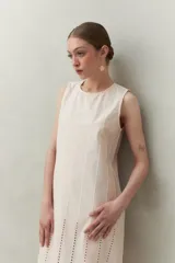 Vestido largo color beige, sin mangas, confeccionado en algodón con calados verticales y bordado tipo ojo de perdiz.