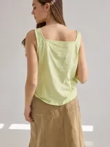 Musculosa color verde claro de lino en el frente y algodón en la espalda, con breteles anchos y escote cuadrado. Presenta detalle de pequeñas perforaciones verticales en el frente.