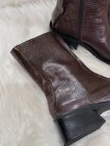Botas cortas color chocolate con textura de cocodrilo, punta cuadrada y tacón bajo. Cuentan con cierre lateral.