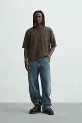 Camiseta marrón de corte holgado, cuello redondo y manga corta. Tiene un efecto lavado y terminaciones irregulares.