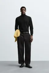 Pantalón negro de corte amplio, tipo balloon fit, con pinzas en la cintura, bolsillos laterales y traseros de ojal.