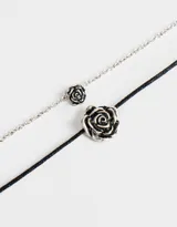Set de dos collares cortos, uno con cadena plateada y dije de rosa plateada, y otro con cordón color borgoña y dije de rosa plateada.