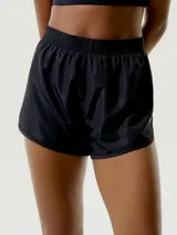 Short deportivo negro, de tela liviana y brillante, con cintura elástica fruncida y corte redondeado en el ruedo.