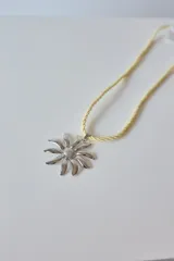 Collar con dije de acero quirúrgico hipoalergénico en forma de margarita plateada y tiento sailor color borgoña.