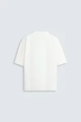 Camiseta verde oscuro de corte holgado, confeccionada en tejido de algodón grueso. Tiene cuello redondo y mangas cortas sin costura en la sisa.