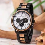 Reloj Chenaut Marmor Noir con caja negra y bisel de madera clara. La esfera imita el mármol blanco con vetas grises y cuenta con cronógrafo, indicador de 24 horas y fechador. La malla combina madera natural y acero inoxidable negro mate.