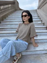 Remera tejida color marrón con hilado 100% algodón y cintas de piedras aplicadas en cuello y mangas.