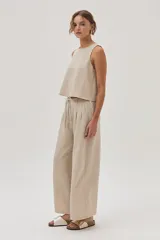 Pantalón de vestir color beige, de corte ancho y tiro alto, con cintura elástica ajustable con cordón.
