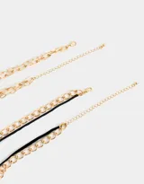 Set de tres collares dorados con diferentes tipos de cadenas y dijes: gargantilla de terciopelo negro con lazo, cadena con dije de corazón y cadena con relicario ovalado con diseño floral.