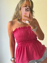 Top strapless de color fucsia con diseño de nido de abeja en el torso y terminación en volado tipo peplum.