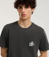 Remera masculina de algodón color gris oscuro, modelo comfort, con cuello redondo y mangas cortas. Estampa frontal con palmeras y lettering "El Cuco" en blanco.