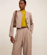 Pantalón de vestir color beige con cintura sencilla, pliegues delanteros y corte palazzo.