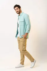 Pantalón cargo color beige, de corte ajustado, con bolsillos laterales con fuelle y cierre de botón a presión.