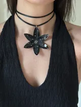 Gargantilla negra con colgante en forma de flor negra con detalles de mostacillas plateadas.