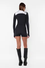 Top deportivo negro de tricot con recortes pisados con bordador, media polera, manga larga con mitones y estampa en lateral del frente y espalda.
