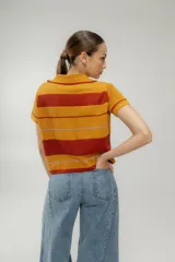 Remera tejida a rayas horizontales color marrón, celeste y blanco, con cuello polo y mangas cortas.