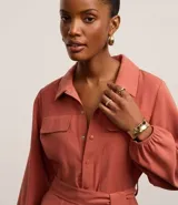 Mono largo color ladrillo, de corte sastrero, con cuello camisero, cierre frontal con botones y cinturón de lazo en la cintura.