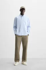 Camisa azul marino de corte regular fit, confeccionada en tejido de algodón Oxford. Tiene cuello abotonado, manga larga con puños abotonados, bolsillo de parche en el pecho y cierre frontal con botones.