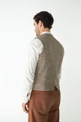 Chaleco de vestir para hombre, color marrón claro con textura tweed. Diseño sastrero con cuello en V, cierre frontal con botones, bolsillos ribeteados y forro interno. Confeccionado en lana fina sin teñir, diseñado exclusivamente por Don Baez.