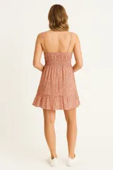 Vestido corto color rosa con estampado floral, breteles anchos y escote recto. Presenta frunces en el busto y falda con volados.