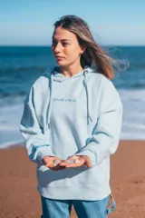 Hoodie celeste con capucha y cordones ajustables, con bordado de la frase "Glassy Waves" en el pecho y un diseño de olas en la manga.