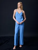 Enterito celeste de crepe marca Luxology, con escote en V cruzado, cintura elastizada, espalda en punto smock y tirantes con detalle de cadenas.