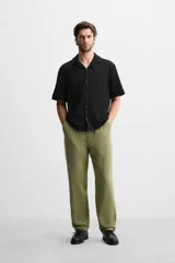Pantalón verde oliva de corte relaxed fit, confeccionado en tejido de algodón con textura. Tiene cintura elástica ajustable con cordón, bolsillos frontales y un bolsillo trasero de parche.