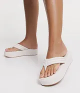 Sandalia tipo ojota de la marca Satinato con plataforma plana de 5 cm. Cuenta con tiras anchas acolchadas con costuras decorativas tipo capitoneado y puntera redonda.