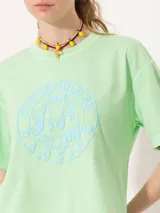 Remera rosa de algodón pima con estampado circular en el frente con la frase 'You Should Be Dancing' y un personaje bailando. Tiene corte amplio, mangas cortas, cuello redondo y tajos laterales.