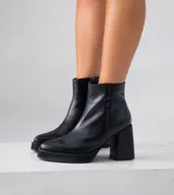 Bota corta negra de cuero vacuno, con taco de madera de 9 cm y plataforma delantera de 2 cm.