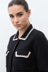 Chaqueta de tejido color terracota/lacre, con cuello y bordes de bolsillo en blanco con textura de punto. Posee cierre frontal de botones y manga larga.