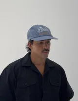 Gorro tipo jockey color azul, con visera curva y bordado frontal que dice "Faded" en blanco y "Sunset Flower Faded Sense Again" en naranja.