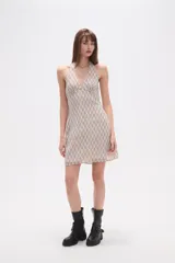 Vestido corto de poliéster, ajustado al cuerpo, con cuello halter y escote en V. Presenta un estampado de cuadros en tonos beige y negro/gris oscuro.