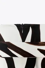 Falda midi de tiro medio con estampado de cebra en tonos marrones y blancos. Cintura con trabillas y cinturón ajustable con hebilla forrada en el mismo tejido. Bajo recto con abertura y cierre con cremallera oculta en la costura.