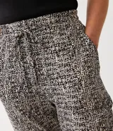 Pantalón capri con estampado tipo tweed en tonos blanco, negro y gris. Tiene corte recto, cintura alta con lazo y bolsillos laterales.