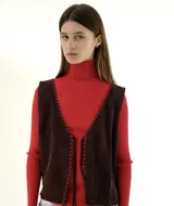 Chaleco marrón chocolate de gamuza con costuras rojas en los bordes.