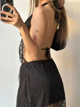 Vestido largo negro de encaje con forro corto, escote halter, espalda descubierta y cinturón con hebilla metálica y tachas.